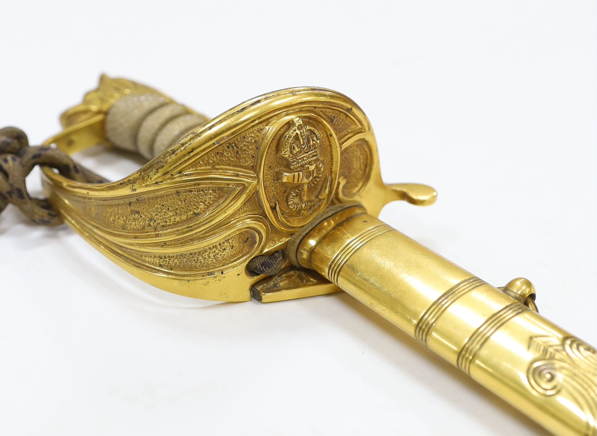 A World War I naval sword with folding guard engraved J.W. Collett R.N., regulation gilt hilt and scabbard mounts, the blade has been refinished and furniture regilded, with bullion dress knot, blade 78.5cm